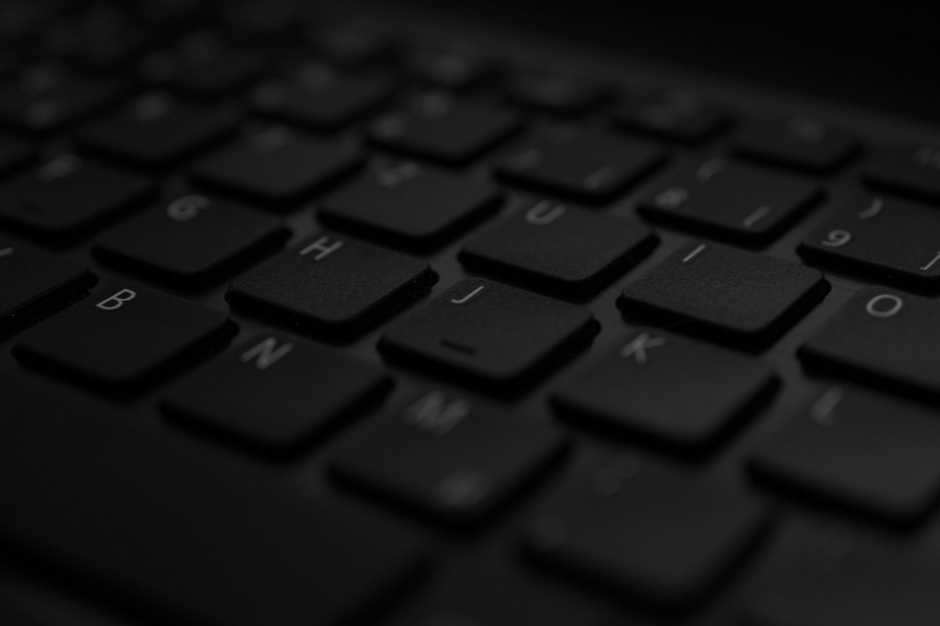 A detailed close-up of a black laptop keyboard with soft lighting and selective focus.